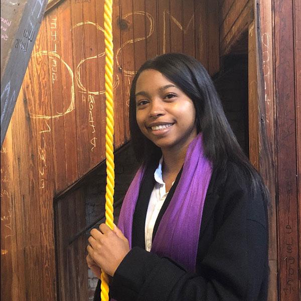 Smiling student holding rope to the bell tower
