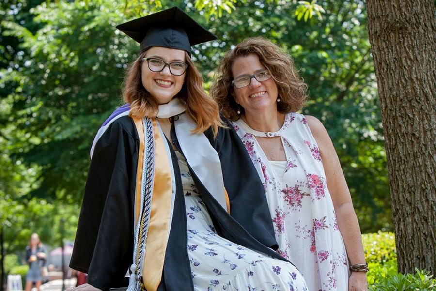 Smiling parent with smiling student in cap and gown